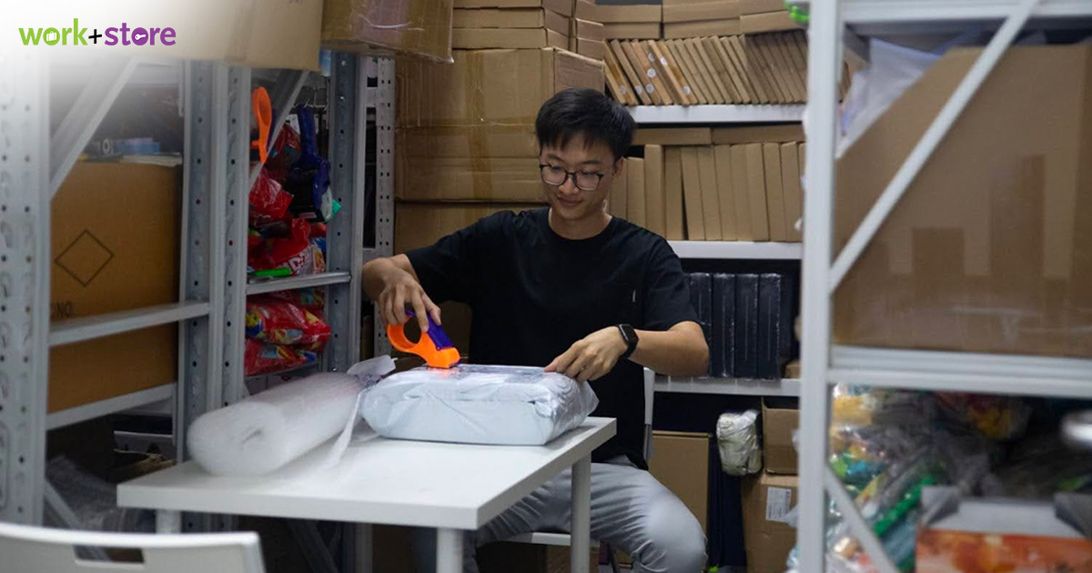  A man packing a parcel in a small storeroom filled with boxes and inventory, inside a Work+Store unit.