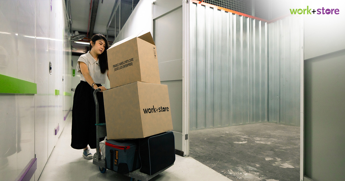 Person pushing trolley with boxes into storage.