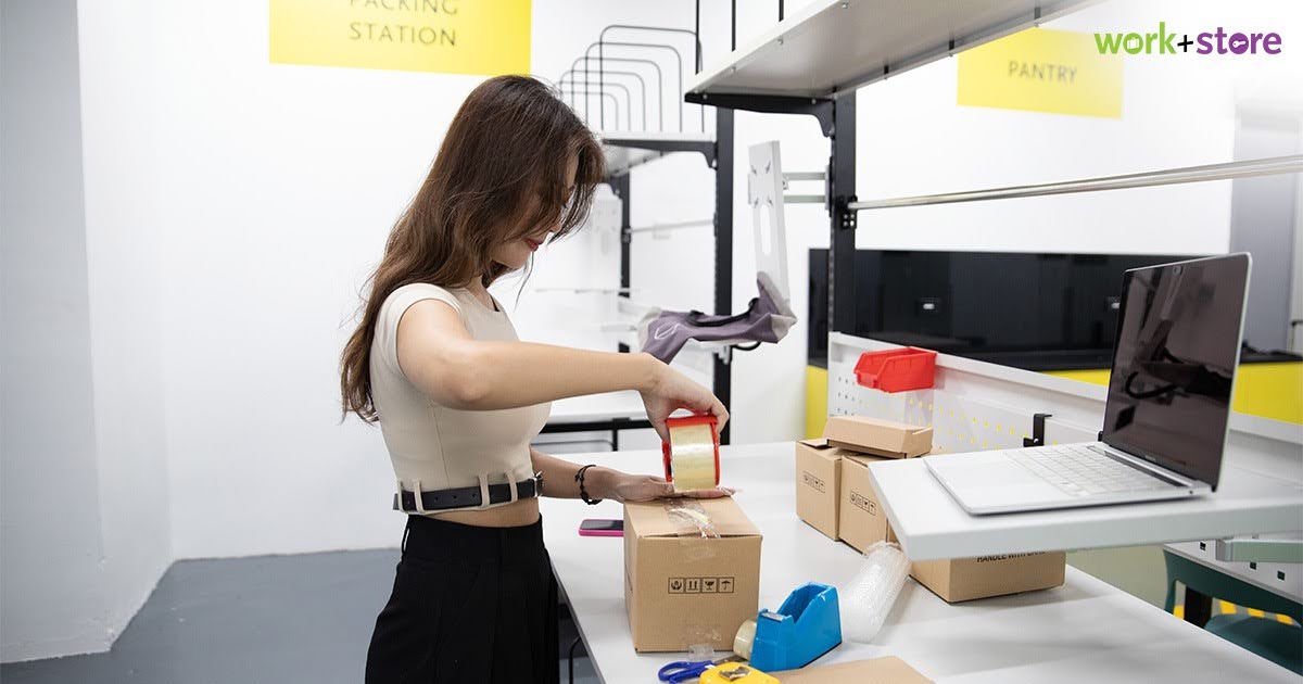 Woman sealing parcel box at ecommerce packing station
